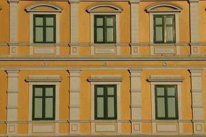 Yellow retro Europe style building and green rectangle shape windows in Bangkok, frame of windows painted dark green color, Thailand. photo