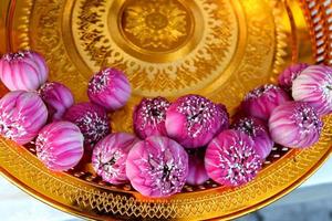 Top view of pink-purple lotus flowers on gold color tray, Thai ancient style in temple, The lotus flower take out of outer petal in round shape, Thailand. photo