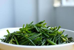 Stir fried Chinese chives flowers on white dish and blur background. photo