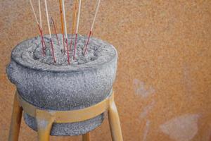 Gray rock incense burner on yellow metal trestle and light brown background, Thailand. Incense pot made simple retro style and joss stick inside photo