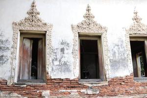 Windows of ancient native church in Bangkok, base of church is broken and open some red bricks, stucco of Thai pattern around the window, Thailand.