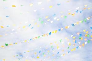 Blue,green, yellow, white triangle flags are on lines and sky background with clouds. photo