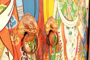 Brass door knobs are on bright colorful door and shape tiger head, the door knobs are design chinese style in shrine, Thailand. photo