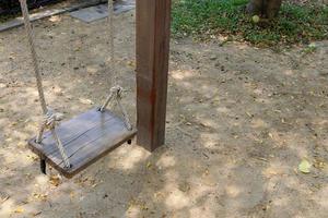 un columpio de madera cuelga sobre el suelo junto a un poste de madera, tailandia. foto