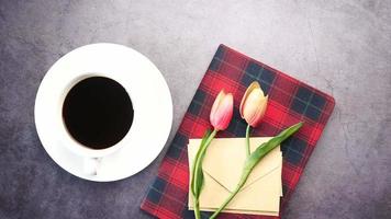 café de composição plana, flor de tulipa e óculos em fundo preto.