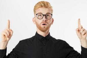 Stylish red-haired man in glasses points up photo