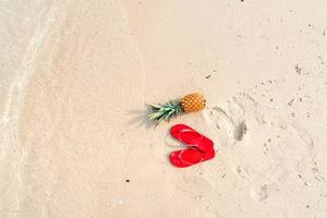 Summer beach vacation with pineapples and flip flops on the beach photo