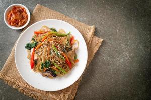 japchae or stir-fried Korean vermicelli noodles with vegetables and pork topped with white sesame