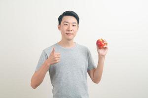 Joven asiático con un vaso de agua y una manzana en la mano foto