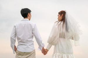 Happy young Asian couple in bride and groom clothing photo