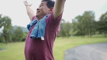 asiatischer reifer Mann, der sich nach dem frischen Morgentraining im Park erleichtert und glücklich fühlt video