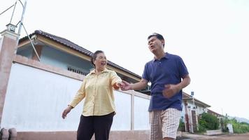 Low angle shot on senior couple holding hands walking in village while elderly man having acute heart attack with supporting of his worried wife, elderly physical medical condition, health insurance