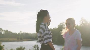 Two young female friends having a good time going out exploring the nature, lgbt pride concept, homosexual couple romantic shkt, feminine society, girls standing by the natural river creek park video