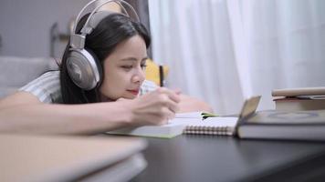 Schöne Studentin, die ein Headset aufsetzt, um Online-Unterricht über eine Handyanwendung zu hören, Fernunterricht zu Hause, im Wohnzimmer auf dem Boden sitzen, schnelle Lernfähigkeit, Theorie der kognitiven Prozesse video