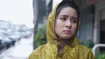 jolie fille asiatique porte un imperméable à capuche jaune coincé sous la pluie, déception face à la pluie battante, temps de la saison des pluies, se sentir triste et solitaire, mauvais chagrin orageux expression du visage malheureux