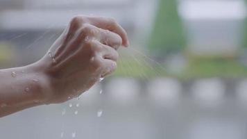 Close up woman hand reaching for the rain drops on heavy raining day, wet hand feeling nature, climate change, monsoon typhoon season, rain droplets slow motion,  air humidity dense h2o compounds video