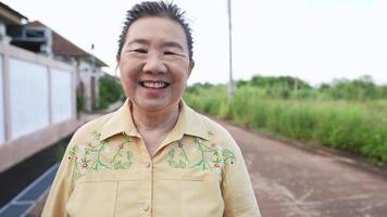 un portrait d'une femme âgée heureuse marchant vers la caméra et souriant avec des rides sur un visage amical, des personnes âgées chaleureuses et gentilles, des soins de santé pour personnes âgées et des exercices relaxants, la grand-mère profite de la vie de retraite video