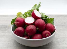 Red radishes in a bowl isolated on wooden background photo