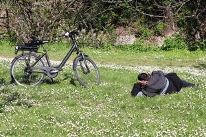 Bologna, Italy, April 18, 2022, Man relaxing on the park lawn. Resting in the park after the pandemic. Bologna, Italy. photo