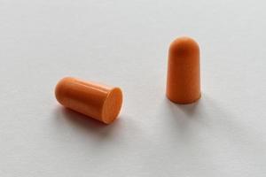 Orange foam ear plugs isolated on white background photo