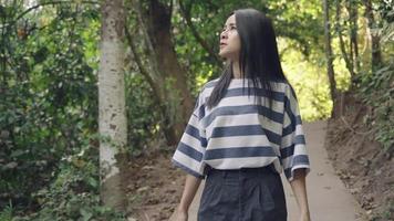 jonge volwassen aziatische vrouw die alleen in het bos loopt, wandeltochten in het nationale park, mens en natuur, buitenactiviteiten nastreven, tropische bossen, wandelen naar de camera op het wandelpad video