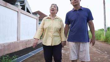 Asian senior couple take a walk and holding hands with relaxing vibe around the neighborhood, active lifestyle, grandparents spending time together, relationship goal, experienced lover, old age care video