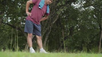 Aziatische actieve man van middelbare leeftijd doet staande heup warming-up oefening, afkoelen na het sporten in het park, lichaamsconditionering gezond leven motivatie na pensionering, staande handen op de heupen rotatie video