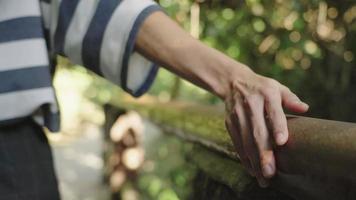 tracking shot van een vrouwelijke hand die de leuning aanraakt, beschermende bewakingsapparatuur tegen vallen, metalen rail vol roest en mos, wandelen in de natuurlijke omgeving, wandelactiviteit video