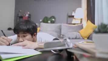Ein erschöpfter Student, der sich langweilt, allein im Wohnzimmer eine harte Hausaufgabe zu machen, sich spät in der Nacht zu Hause auf Prüfungen vorzubereiten, auf dem Schreibtisch einzuschlafen, einen anstrengenden Tag mit Büchern zu lesen, gestresst video