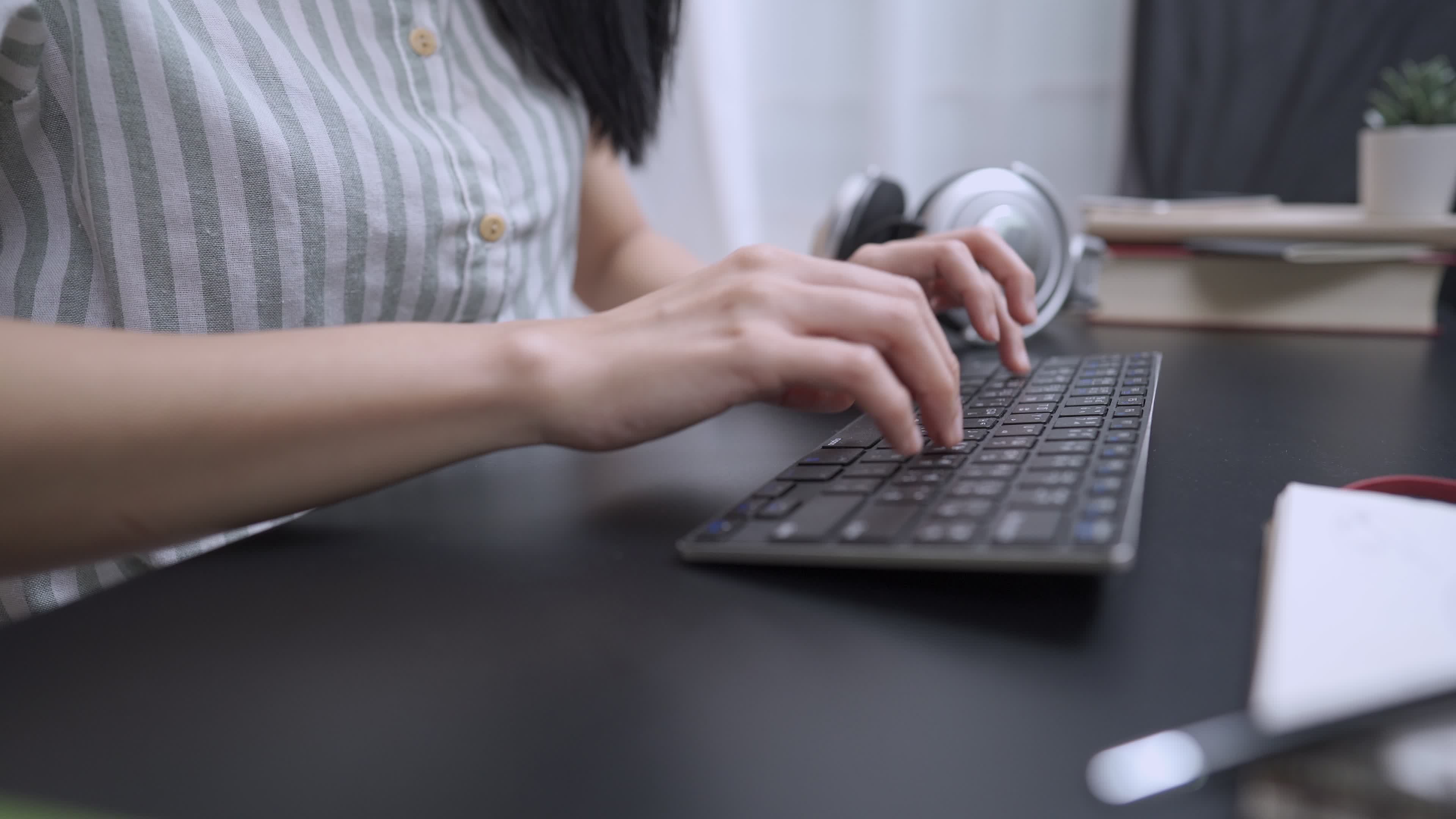 close up female hands typing on wireless keyboard, working at home