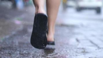 flou d'arrière-plan tourné en cours d'exécution flipflop le jour de la pluie, sur la rue à pied, rue inondée, avec pluie et eau, partie inférieure du corps, hâte de courir trouver l'abri pour cacher la pluie