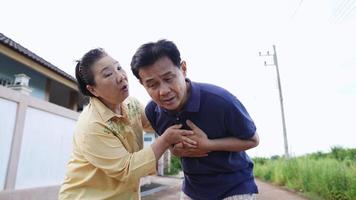 elderly man holding hand on breast touch chest having heart attack feels unwell with worried wife supporting, acute myocardial infarction symptoms, health problems medical insurance video