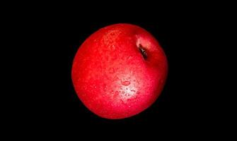 Water droplet on glossy surface of red apple on black background photo