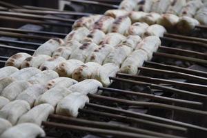 Bananas are on bamboo skewer. Row of bananas are roasting on fire, Thailand. photo