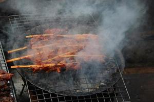 Chicken clamping bamboo piece are grilling on stove and smoke, favorite street food in Thailand. photo