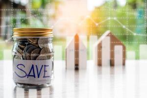 Coins and text SAVE in a glass jar placed on a wooden table. Concept of saving money for investment and buy a home Or save during the coronavirus COVID-19 outbreak. Copy space, Blurred background photo