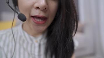 agente feminina asiática call center vista frontal close-up usar microfone de fone de ouvido fazendo teleconferência com cliente, trabalhador de escritório em casa, entrevista de emprego ou cursos on-line à distância, serviço de assistente de consultor video