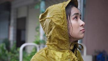 jonge aziatische vrouw draagt een gele regenjas met capuchon zich neerslachtig teleurstellen met stromende regen, regenseizoen weer, zich blauw verdrietig en eenzaam voelen, hevig stormachtig bezorgd angstig vast in de regen, natte kleren