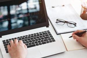 Businessmen work with stock market investments using laptops to analyze trading data. desktop computer with stock exchange graph on screen. Financial stock market. Analyzing data in office background. photo