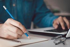 hombre de negocios calculando dinero, planificación de dinero, presupuesto de préstamo, concepto de pago en línea en computadora, papeleo de trabajo en el escritorio de casa. foto