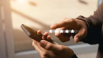 A male customer gives a five-star rating on their smartphone, satisfaction, customer service experience. Service Rating Reviews and Satisfaction Survey Concept. photo