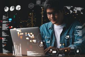 businessman financial analyst using laptop working at the office at night, graph interface, virtual screen, connection icons, digital diagram concept. photo