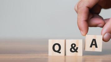 Hand holding Q and A words with wooden cube blocks , answers, ask questions, information,FAQ. photo