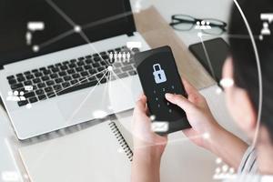 Hacking a Phishing mobile phone with a password to access a smartphone, security threats online, and fraud. A young man with a cell phone and laptop is secure in his bank account.