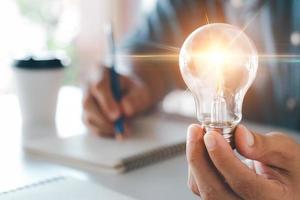 Innovation through ideas and inspiration ideas. Human hand holding light bulb to illuminate, idea of creativity and inspiration concept of sustainable business development. photo