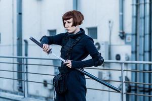 portrait of young redhead woman with japanese sword dressed in futuristic cyberpunk costume standing on the roof. photo