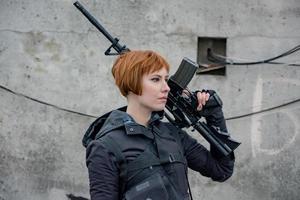 mujer joven en estilo moderno de tecnología negra con rifle posando en la azotea, retrato de mujer pelirroja cyperpunk o concepto postapocalíptico
