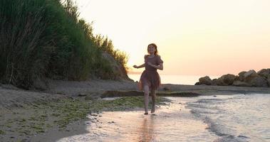 mujer joven vestida relajándose en la playa de verano durante el hermoso amanecer