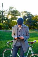 joven hipster masculino lee un libro en el parque de otoño foto