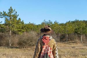 Yong hipster woman traveler in hat and poncho walking outdoors photo